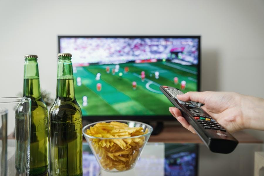 Person watching TV with drinks and food
