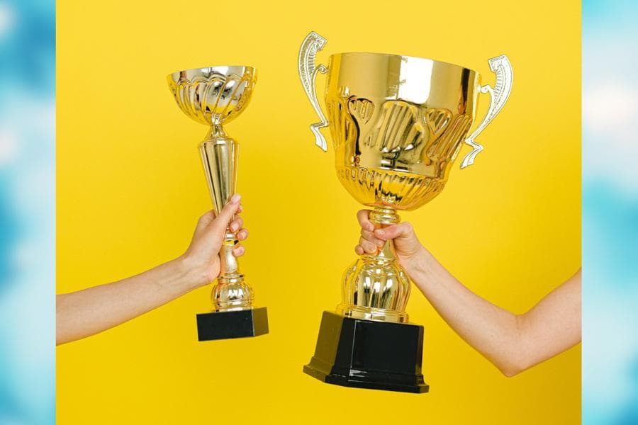 Two people holding large trophies